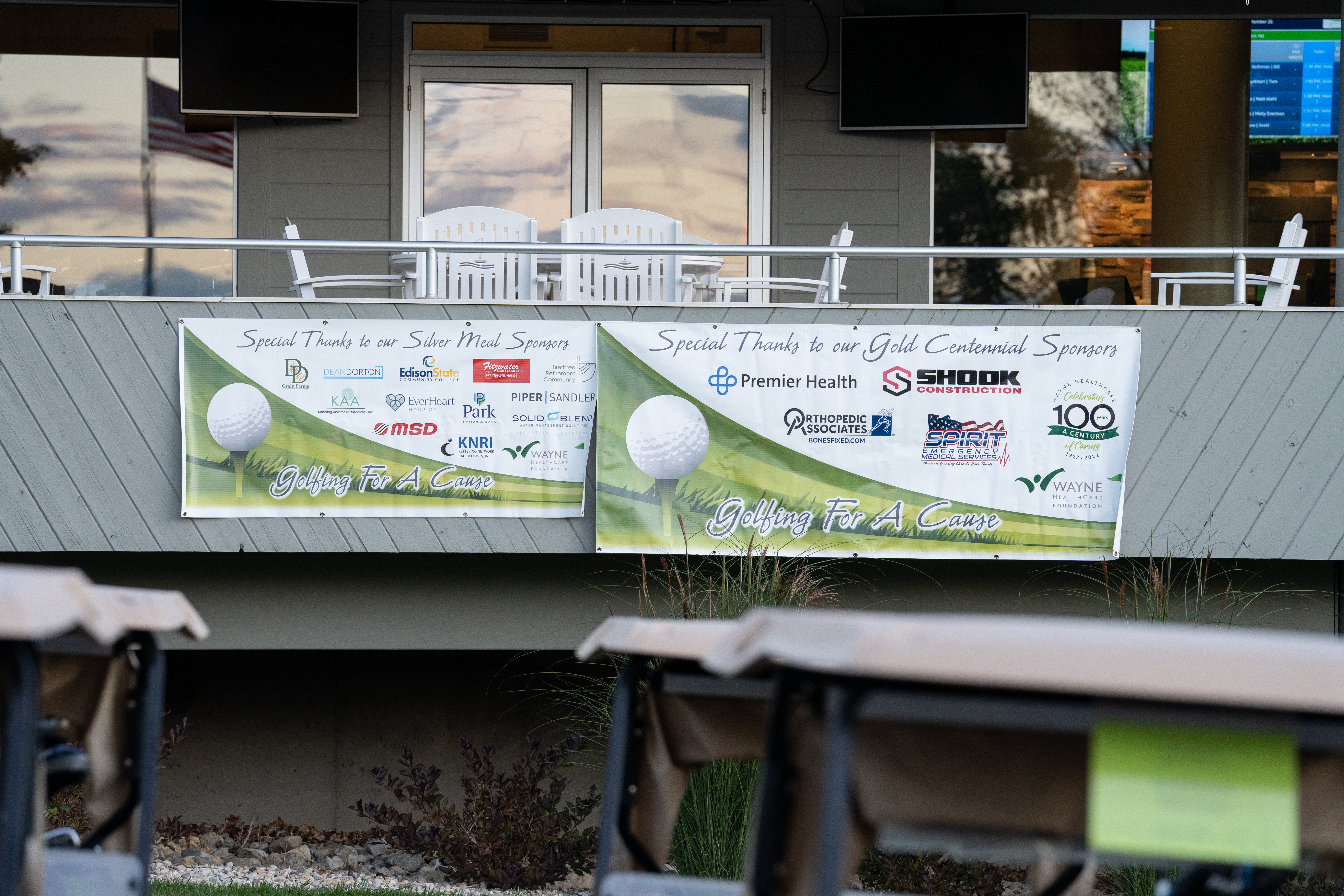 Porch with Chairs Golf Sponsor Banners hanging off balcony and tops of golf carts